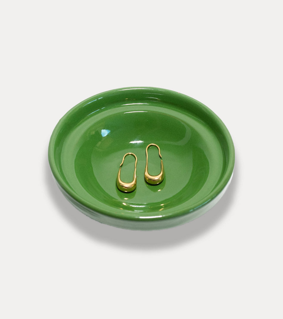 Minimalistic gold earrings on green plate