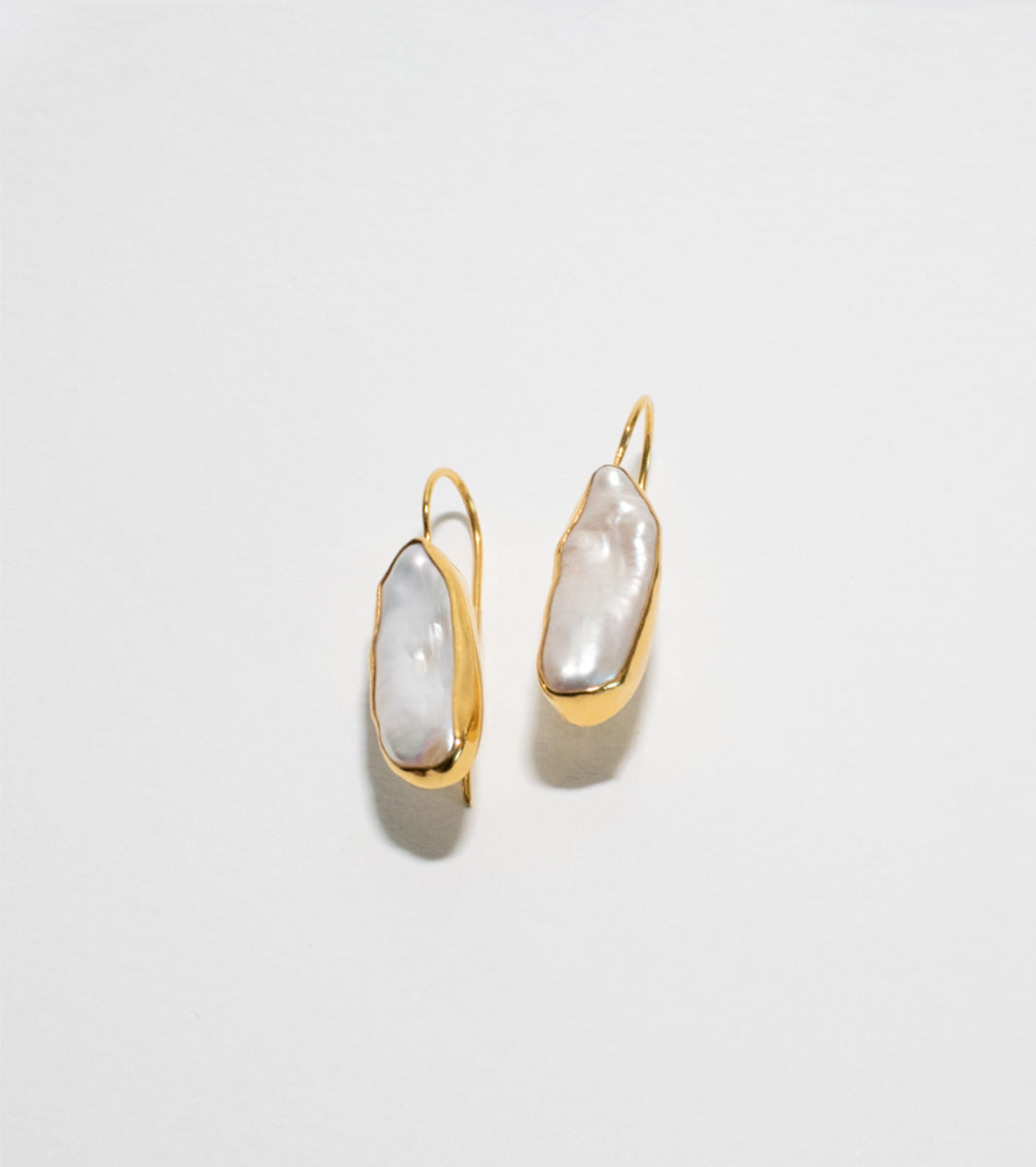 Gold plated pearl earrings on white background